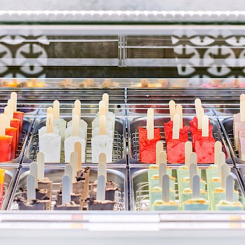 Various colorful popsicles arranged in a display case, featuring different flavors and colors, ready for customers to enjoy.