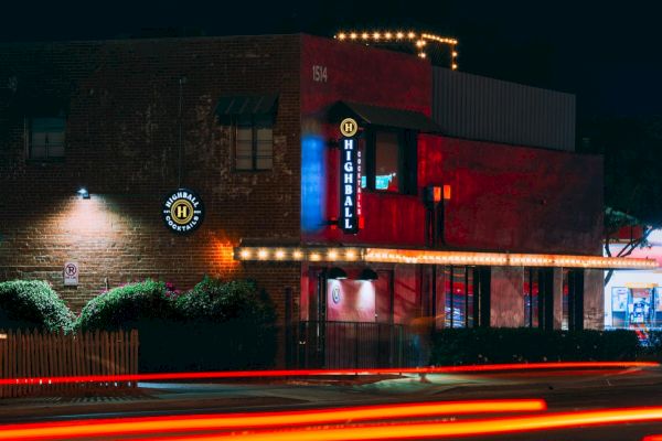 Nighttime photo of a brick building with neon signs reading 