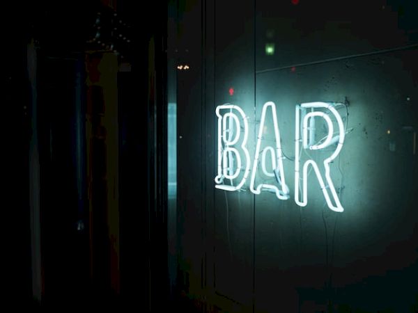 A glowing, neon "BAR" sign is illuminated against a dark background, giving a vibrant and inviting feel to the location.