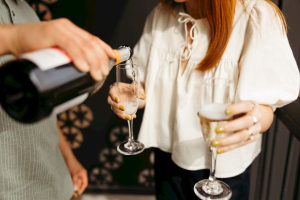 Two people pouring and holding champagne glasses in a social setting.