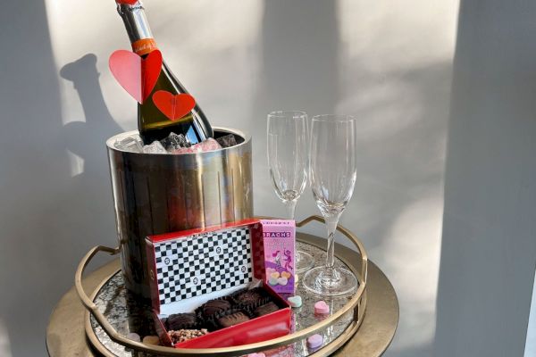 bottle of prosecco with red hearts next to box of chocolates.